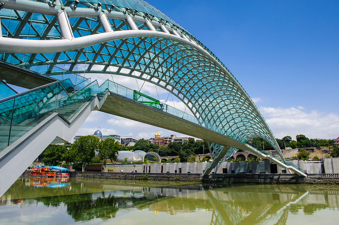 Topic is Travel Destination to the Country Georgia. Bridge of Peace in Tbilisi, Geaorgia, bow-shaped pedestrian bridge over the Kura River in Tbilisi, capital of Georgia. One of the most important sites of Tbilisi.