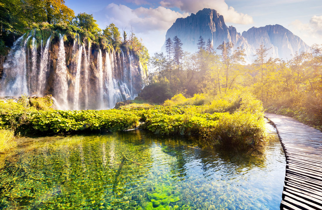 Enchanting Plitvice Lakes National Park: Majestic waterfall, turquoise water, and sunlight illuminating the forest. Croatia.