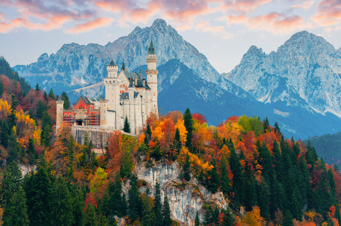 Topic is Travel Destination to Germany. Picturesque Autumn view on Neuschwanstein Castle with colorful trees and foliage.