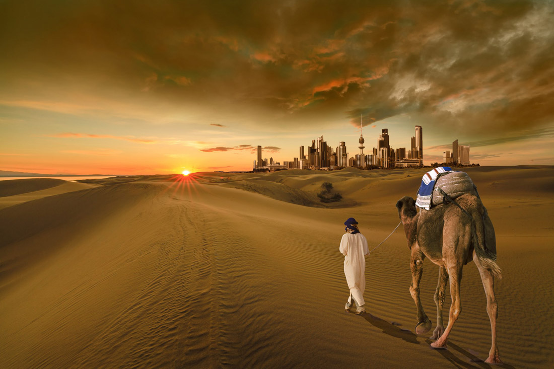 Topic is Travel Destination to Kuwait. A man with a camel walking with view of a beautiful sunset.