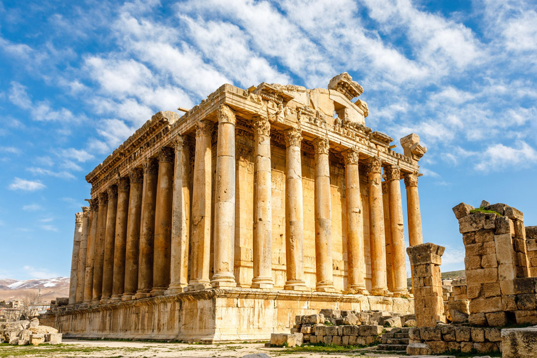 Topic is Travel Destination to Lebanon. Ancient Roman Temple of Bacchus with surrounding ruins with sunny blue sky and clouds above.
