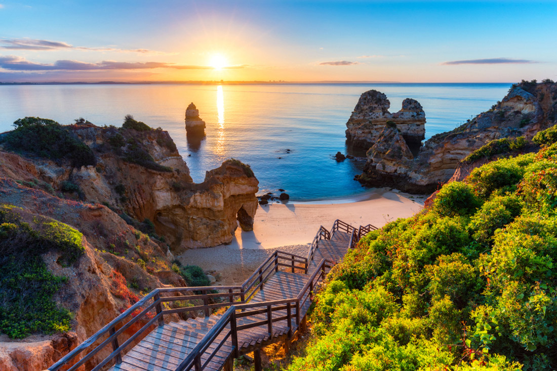 Topic is travel destination to Portugal. Camilo Beach (Praia do Camilo) at Algarve, Portugal with turquoise sea in background. Wooden footbridge to beach Praia do Camilo, Portugal. Wonderful view of Camilo Beach in Lagos, Algarve, Portugal.
