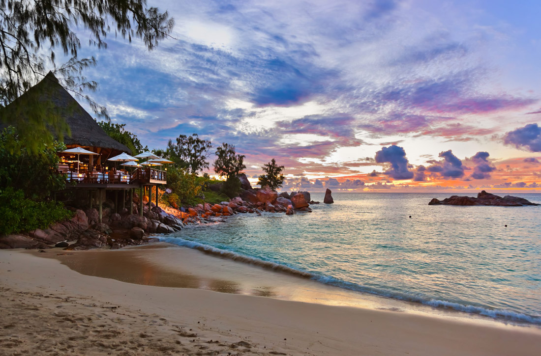 Topic is Travel Destination to Seychelles. Nature background, cafe on Seychelles tropical beach at sunset.