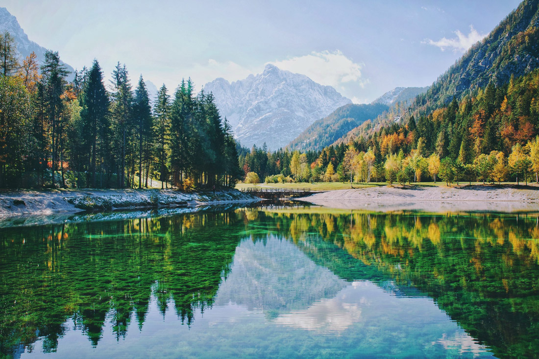Topic is Travel Destination to Slovenia. Autumn Alps Mountain in daylight reflect calm waters.