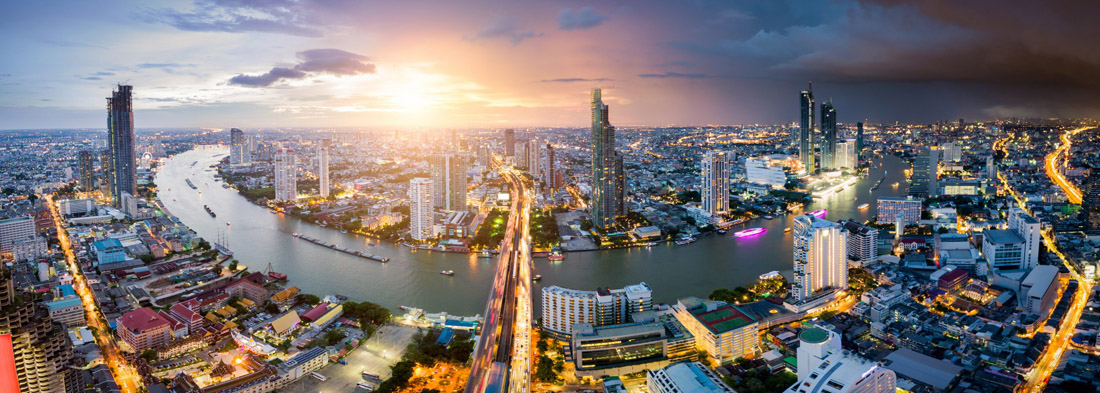 Topic is Travel Destination to Thailand. Aerial view of Bangkok skyline and skyscraper with light trails on Sathorn Road center of business in Bangkok downtown. Panorama of Taksin Bridge over Chao Phraya River Bangkok Thailand at sunset.
