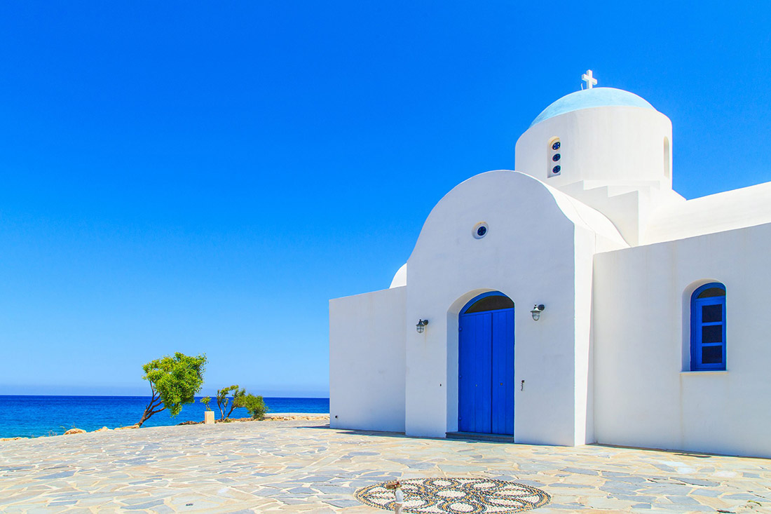 White chapel in Protaras, Cyprus, stands by the azure Mediterranean Sea. Serene beauty amid picturesque surroundings.
