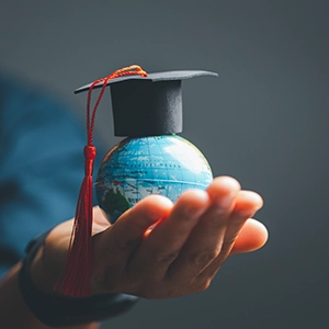 Education News and Insights. Hand holding a world globe with a graduation hat.